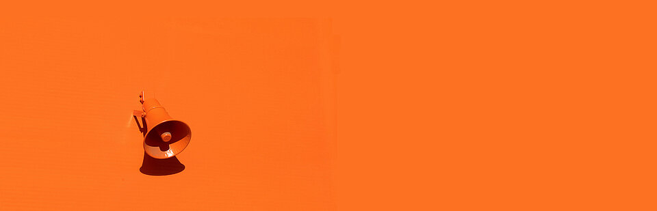 Ein orangefarbenes Megafon auf orangefarbenem Hintergrund. (Bild: © Oleg Laptev/Unsplash)