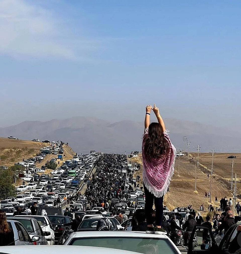 Eine unverschleierte Frau steht auf einem Auto. © IMAGO/ZUMA Wire
