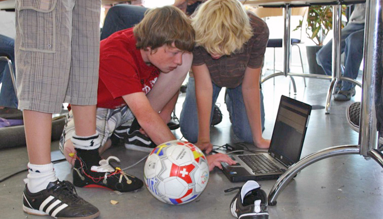 KInder hocken auf dem Boden mit Laptop und Fußball (Foto: privat)